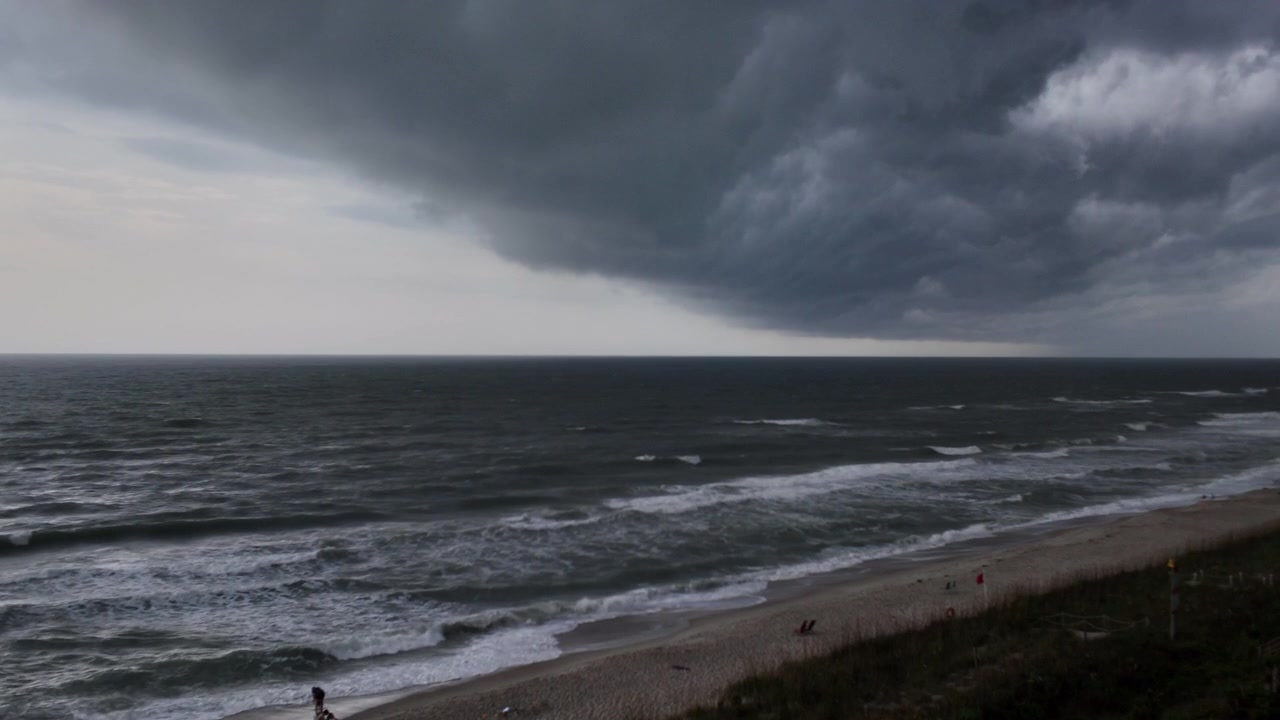 Un fronte temporalesco in arrivo si muove attraverso l'orizzonte oceanico mentre nuvole di pioggia intense si addensano sopra l'acqua scura e aperta.