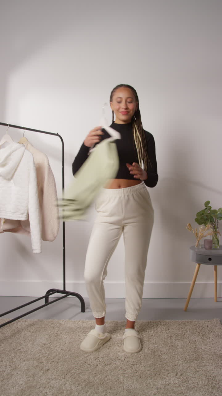 video vertical editado con cortes de salto de una influencer femenina de redes sociales produciendo contenido generado por el usuario en el estudio modelando diferentes trajes de moda 1