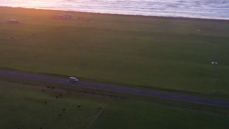 aerial over a car driving along a lake or shoreline in the south island of new zealand