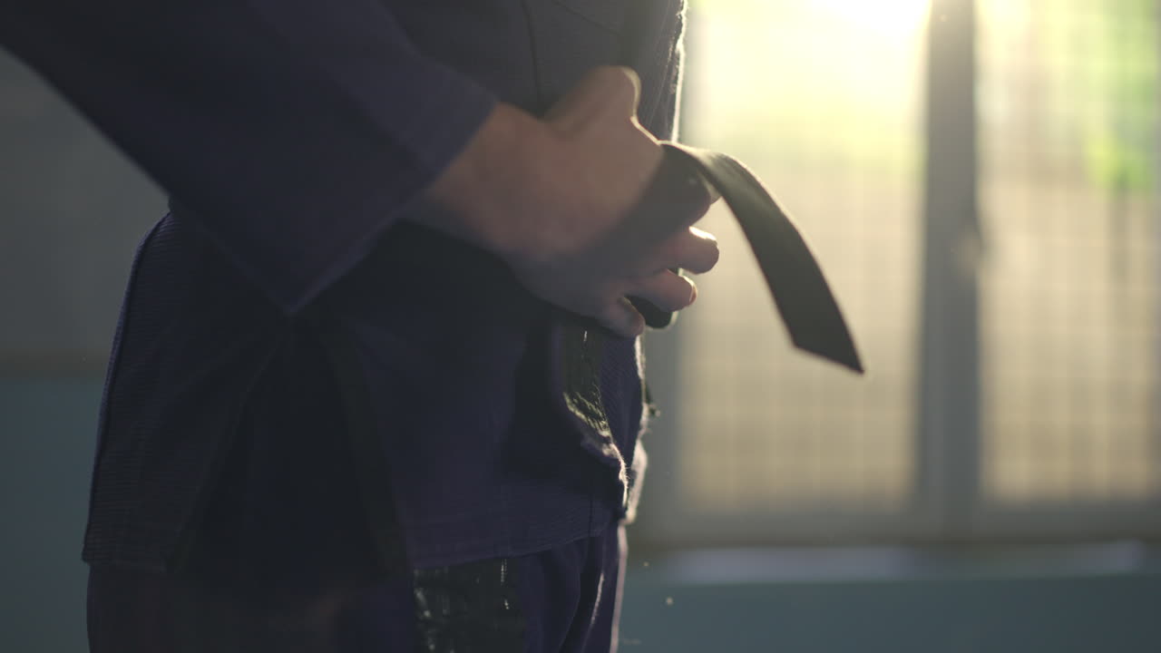 Martial artist tying black belt