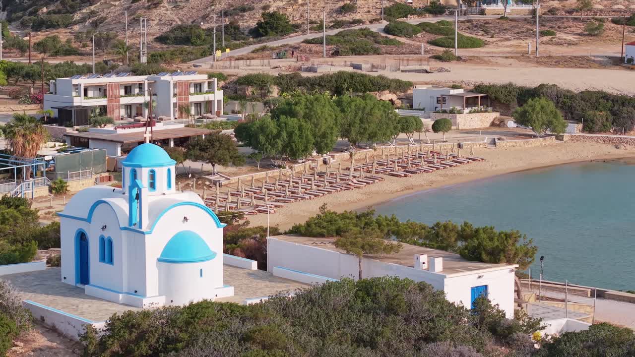 Revealing Amopi Beach in Karpathos, with golden sand, beach loungers, and the iconic white chapel in the background