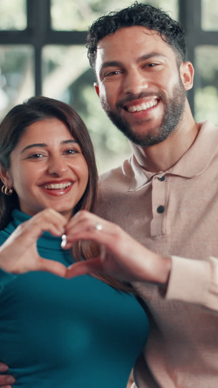 Casal feliz sorrindo e fazendo um formato de coração com as mãos