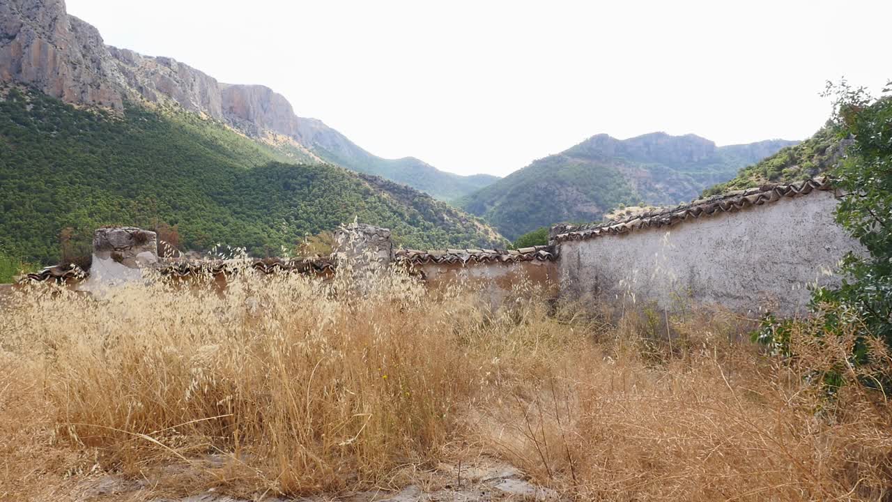 Abandoned cemetery of Otiñar (Jaén), with ruins and tombs at the foot of a large rocky mountain