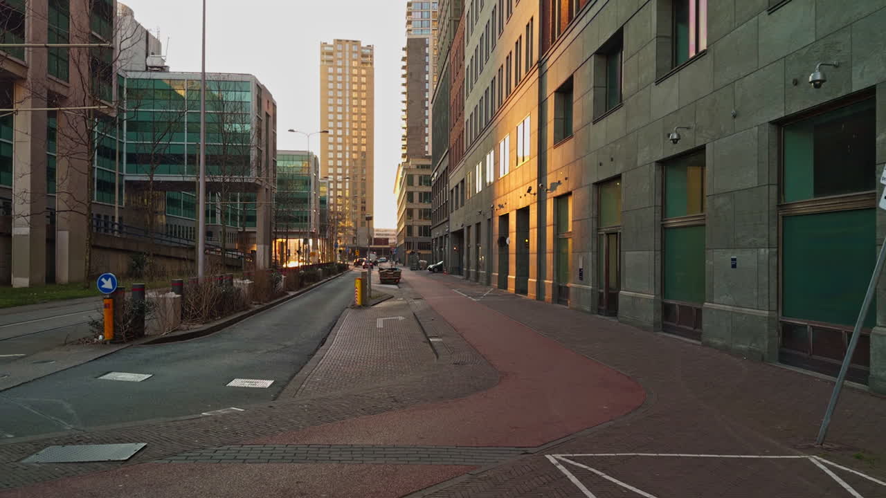 Calle de ciudad urbana europea moderna en los Países Bajos, en La Haya, con edificios y rascacielos durante la hora dorada, al anochecer, antes de la puesta de sol, con vista de ángulo bajo y amplio