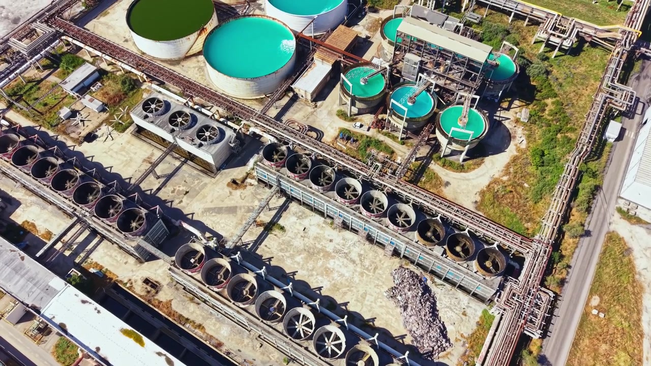 Industrial plant located in a rural area with large tanks and cooling systems near the road on a sunny day in clear weather
