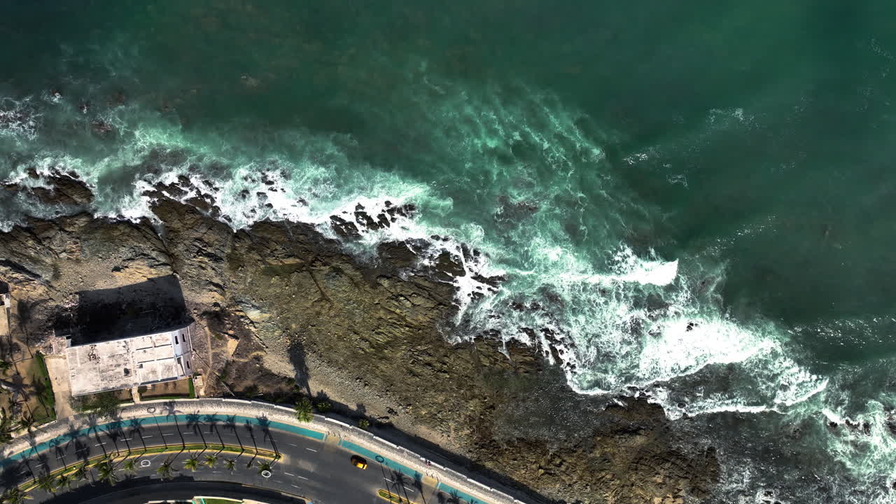 drone de arriba hacia abajo disparado por encima del malecón de mazatlan y las olas, en el soleado méxico