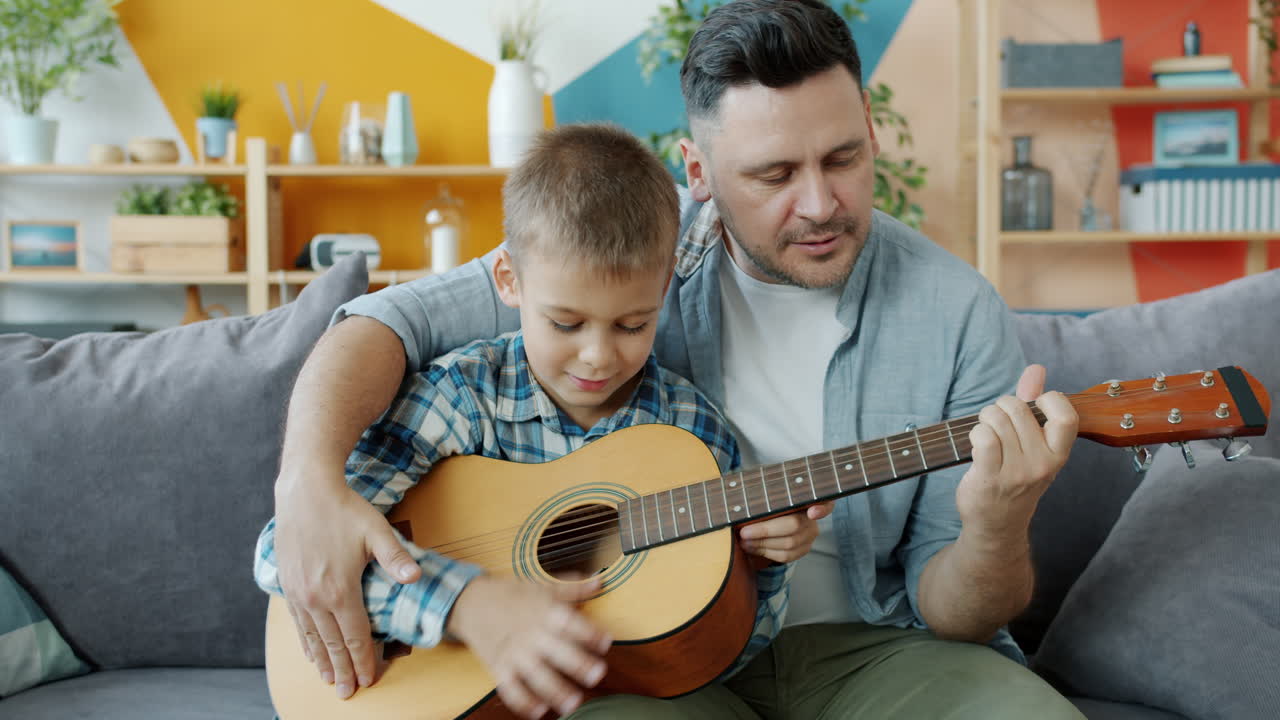 Father and son learning guitar together at home
