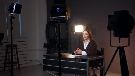 emotional caucasian woman talks confidently to camera in modern photo studio. soffits stand around the reporter.