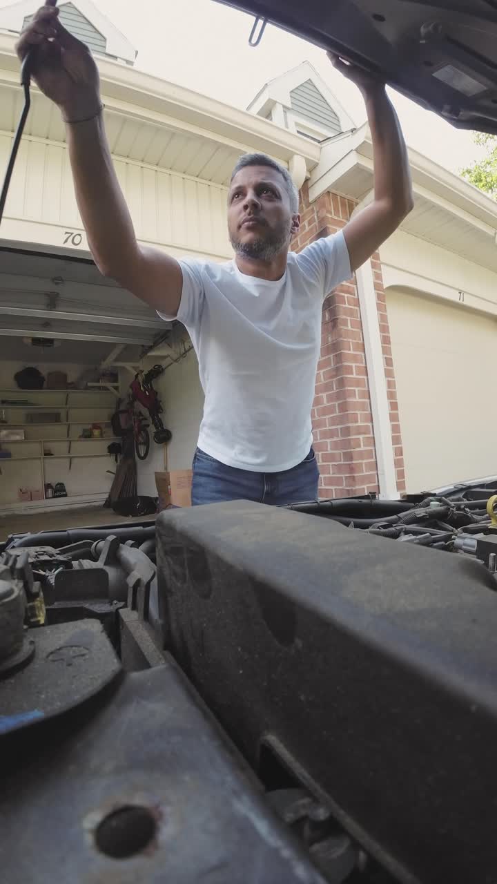 Man Inspecting Car Engine in Front of Garage