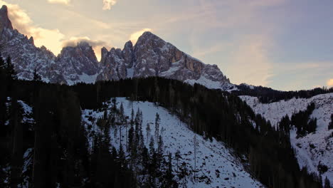 beautiful sunset over snowy mountain peaks and forested hills, creating a serene and picturesque winter scene