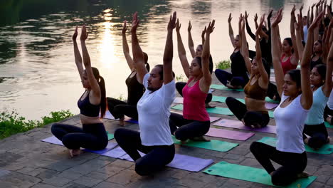 group yoga session by the river at sunset