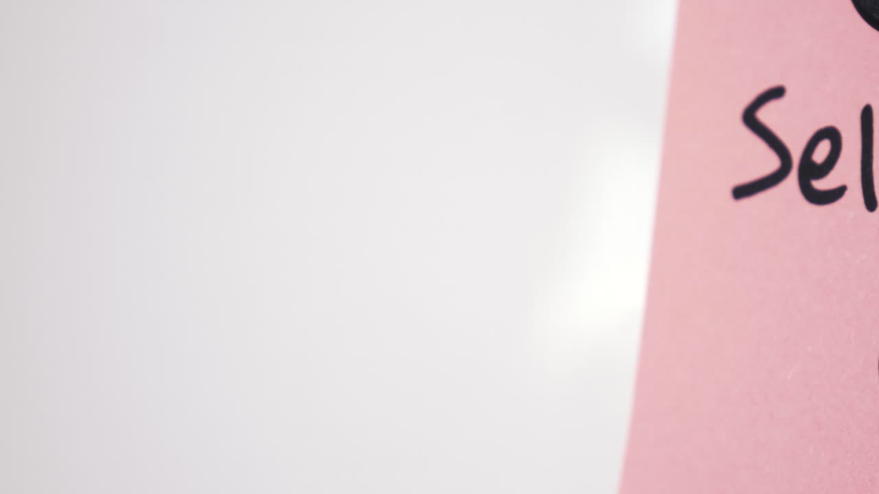 Panoramica testuale di Self Care su un appunto rosa tenuto da un magnete su una lavagna con messa a fuoco selettiva