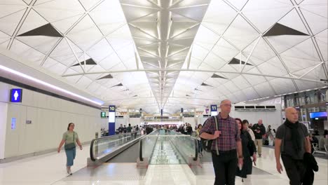 hong kong international airport terminal interior with passengers on moving walkways