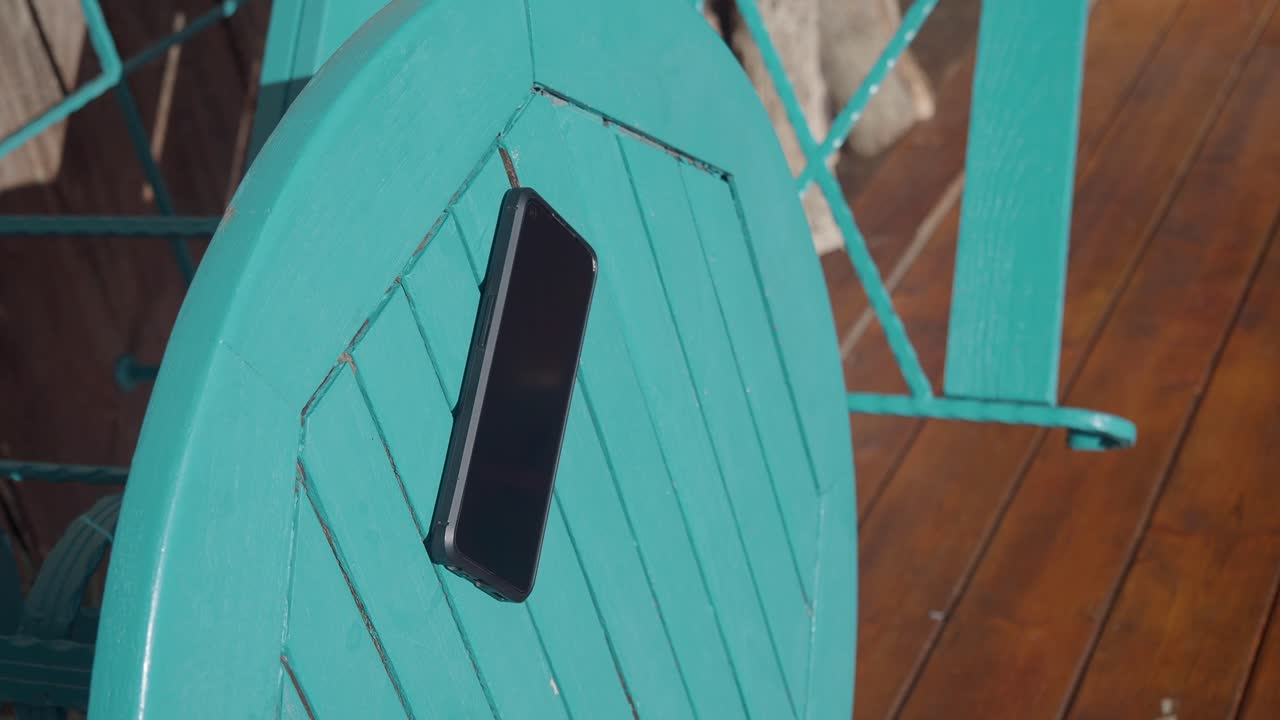 Black Smartphone on an Outdoor Teal Wooden Table