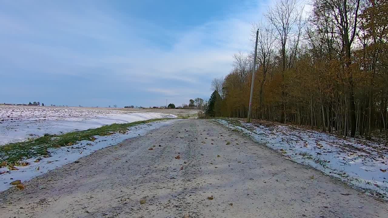 화창한 겨울 오후에 목재와 농가를 지나 시골의 눈 덮인 자갈길을 운전하는 동안 뒷창을 통해 pov