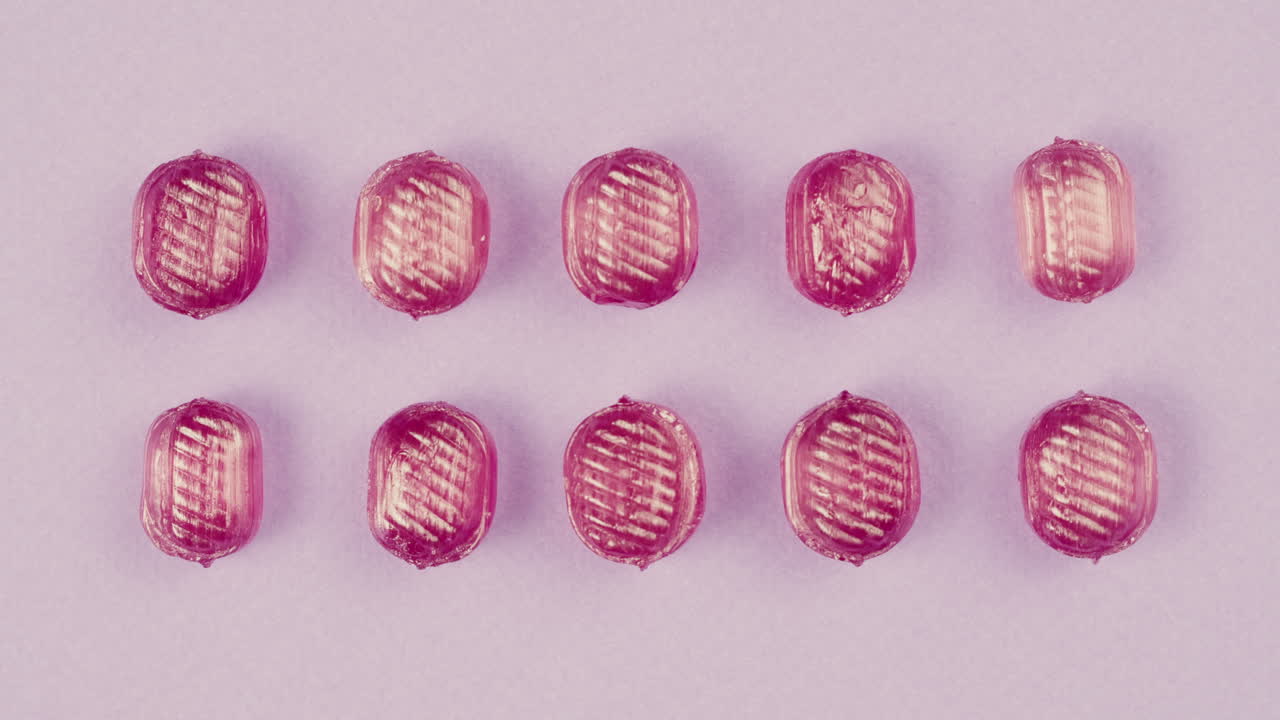 Pink lollipops, candies, bonbons on purple background. Summer bright texture studio shot for store, supermarket, close up top view. Children's favorite sweets made of sugar.