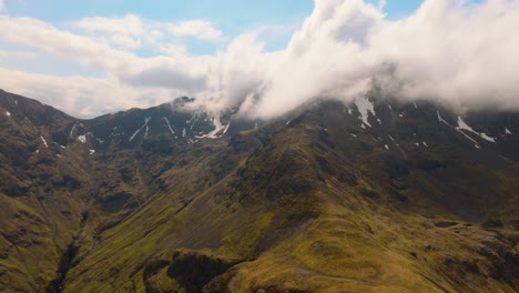 aerial drone footage of bidean nam bian, the highest mountain in glencoe, scotland, covered in snow. sweeping views of snowy peaks, deep valleys, and dramatic highland scenery