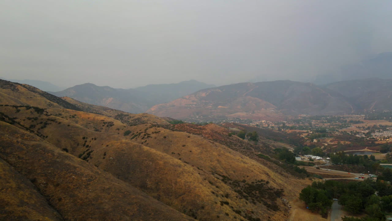 Paesaggio nebbioso di colline ondulate e aride e valle distante