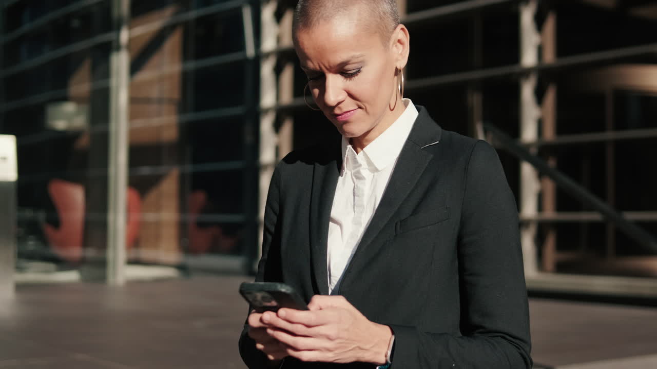 Donna concentrata in tailleur che usa lo smartphone fuori dall'ufficio