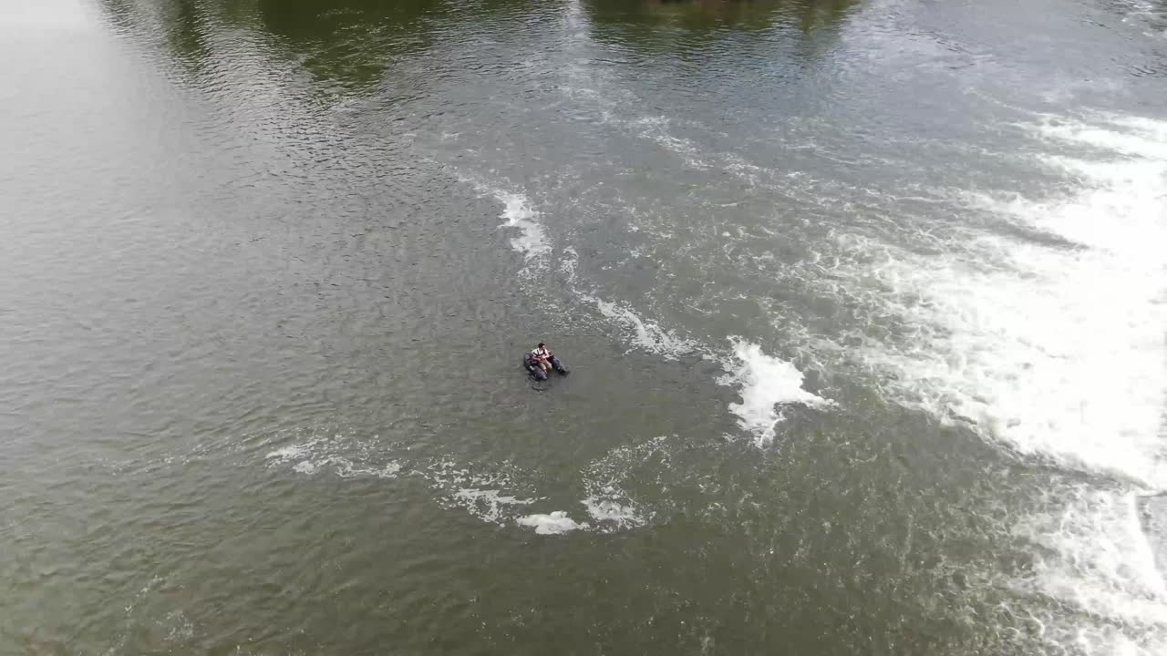 Fisher on a belly boat near a waterfall on a big river. Aerial footage above Pisuerga river in Valladolid