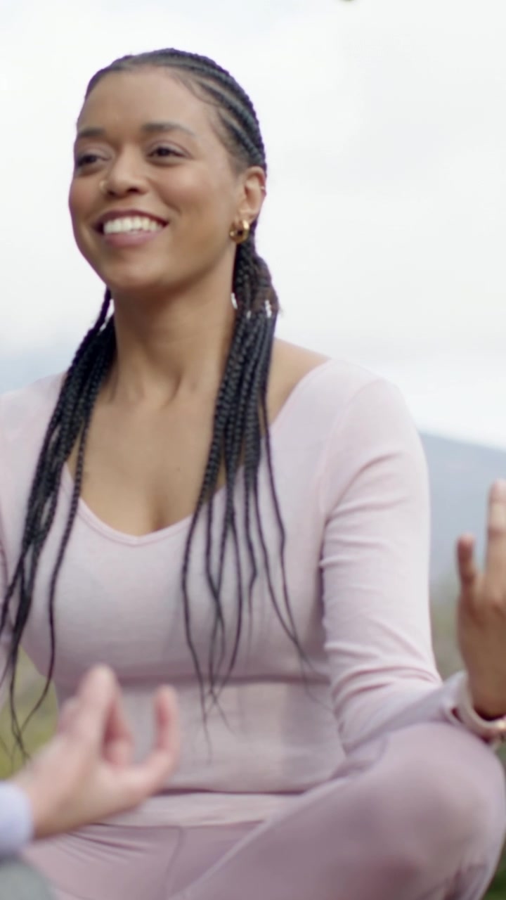Vertical video: Session starting woman in pink doing mudra opening eyes smiling on hills for calm