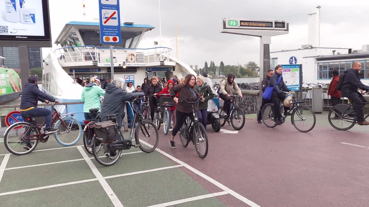 Cyclists and pedestrians getting of the ferry on a rainy day in Amsterdam, The Netherlands