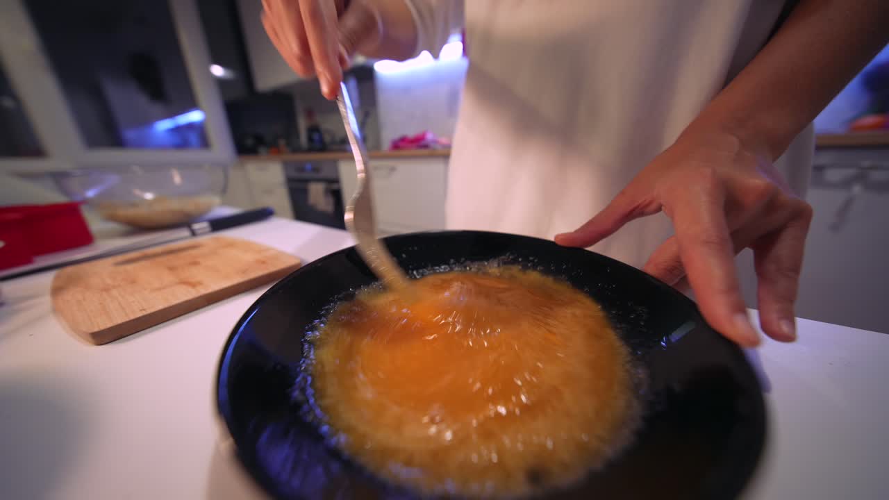 Close-up of Hands Whisking Eggs in a Black Bowl