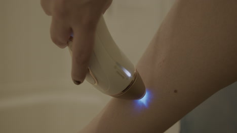 cerrar la cámara lenta de una mujer usando un dispositivo de depilación de luz pulsada intensa en su pierna