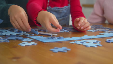 Nahaufnahme-Von-Enkelkindern-Mit-Großeltern-Am-Heimischen-Tisch,-Die-Gemeinsam-Puzzles-Machen