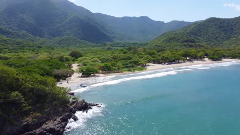 Serena-Playa-Con-Barcos-Anclados-En-El-Parque-Nacional-Tayrona,-Rodeada-De-Exuberantes-Montañas.