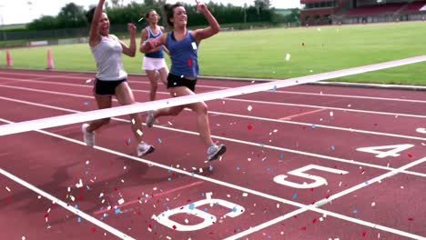 video compuesto digital de confeti multicolor cayendo contra tres mujeres que terminan una carrera