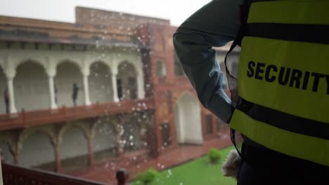 Man-wearing-a-security-vest-inside-the-Agra-Fort-during-a-heavy-rain-in-India