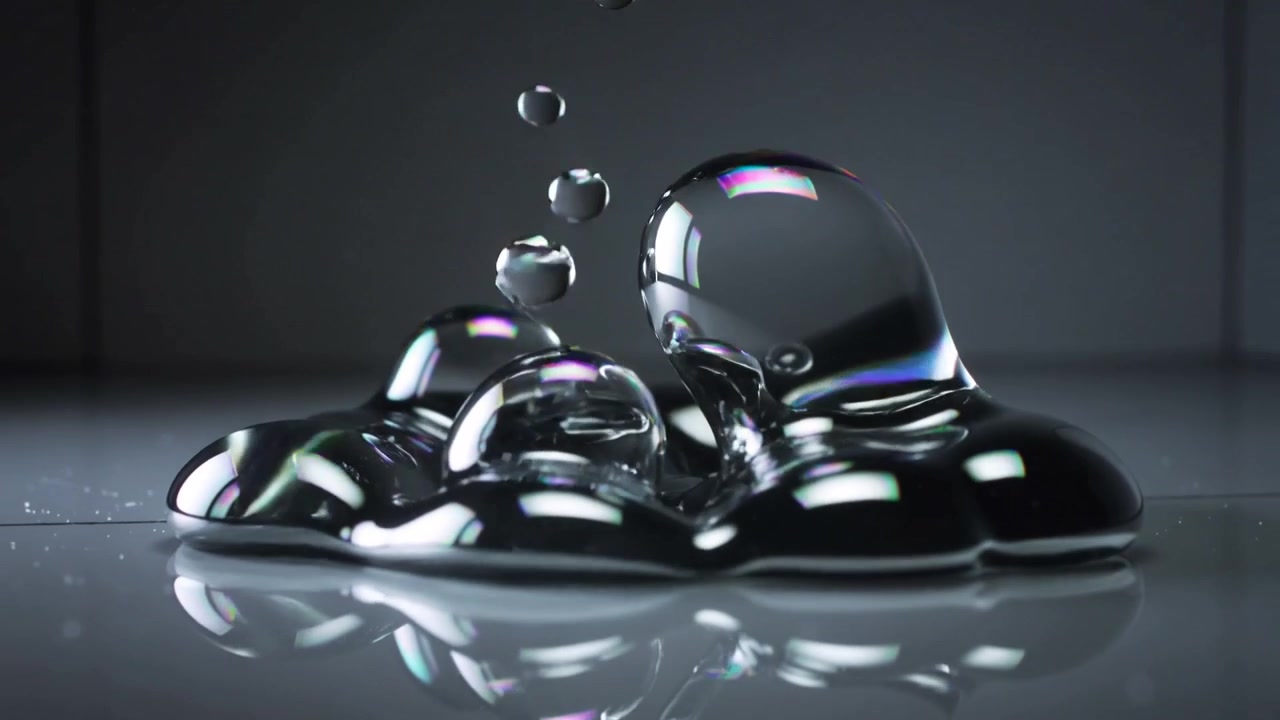 Dropping thin liquid column creating jets and bubbles on studio table puddle, with iridescent sheen