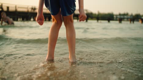 back view of the boy's legs are jumping through the waves