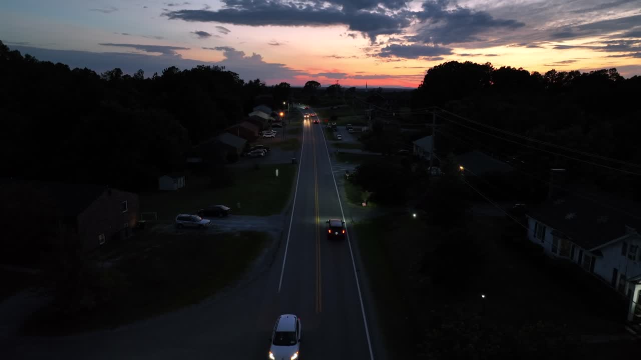 Traffic on sunset time in American suburb. Aerial wide shot. Driving cars on intersection road. Panorama view. Peaceful landscape with houses and homes in Summer