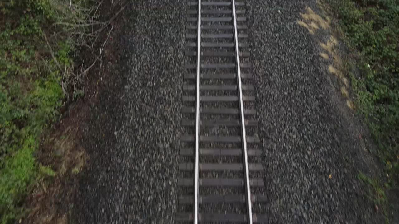 Aerial moving Pan up of a train track alongside of a road that's empty and picks up speed up forward in Washington
