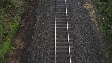Aerial moving Pan up of a train track alongside of a road that&#039;s empty and picks up speed up forward in Washington