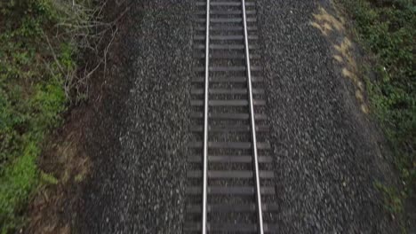 aerial moving pan up of a train track alongside of a road that's empty and picks up speed up forward in washington