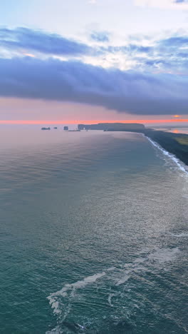 pointed rocks with some moss growing on stick out from the waterscape. top view on the line of land deepening into the seascape. iceland nature. vertical video.