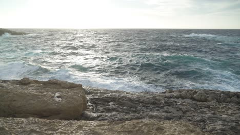 limestone beach with waves crashing on shore of gozo island during windy day in december