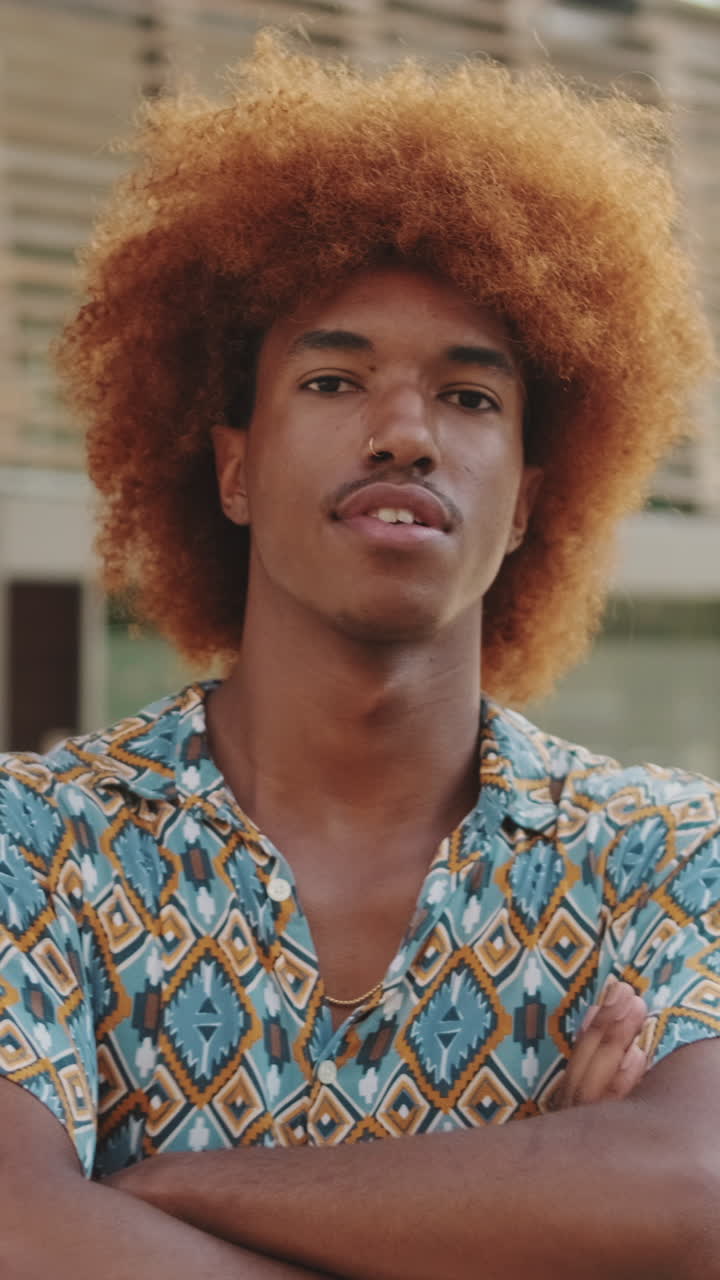 Giovane uomo sicuro di sé con capelli afro che guarda la fotocamera