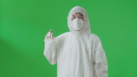 asian man wearing personal protective equipment uniform ppe, medical face mask and holding a glass of test tube in the green screen studio