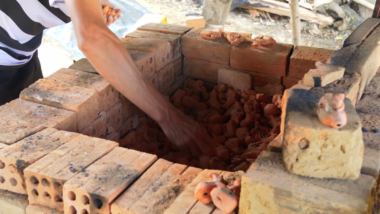 가마에서 점토 조각상을 제거하는 동남아시아 도예가의 중간 후면