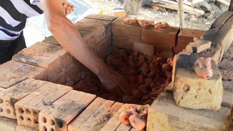 medium rear view of southeast asia potter remove clay figurines from kiln