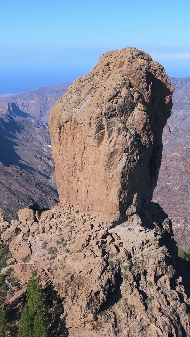 Splendida prospettiva aerea che mostra l'iconico Roque Nublo, una formazione rocciosa vulcanica. Escursionisti irriconoscibili sono visibili alla sua base