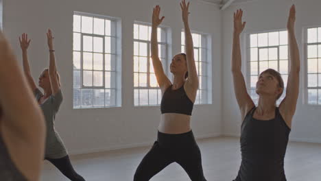 yoga class instructor teaching healthy pregnant women practicing warrior pose enjoying group training exercise in fitness studio at sunrise