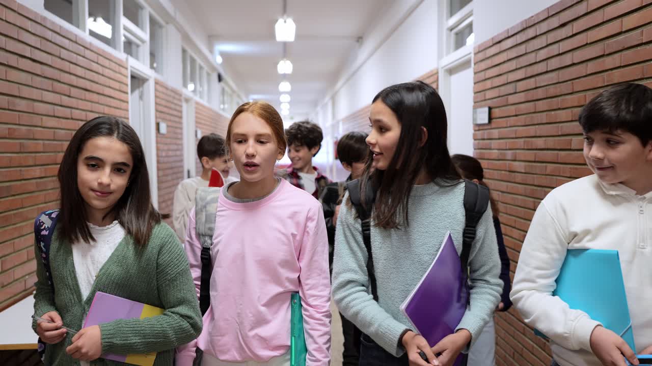 Grupo diverso de jóvenes estudiantes caminando por el pasillo de la escuela