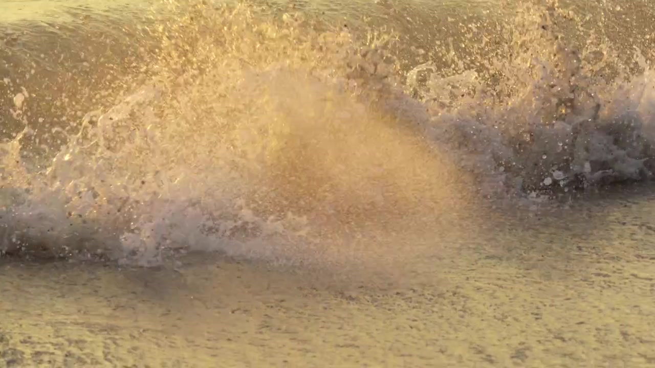 Filmato cinematografico in 4K di onde marine che si infrangono su una suggestiva costa tropicale durante un tramonto dorato. Le placide increspature della marea oceanica sotto un cielo arancione, perfette per progetti di viaggio e natura.