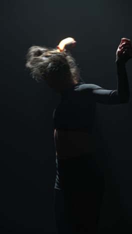 bailarina que realiza un poi de fuego en un entorno oscuro