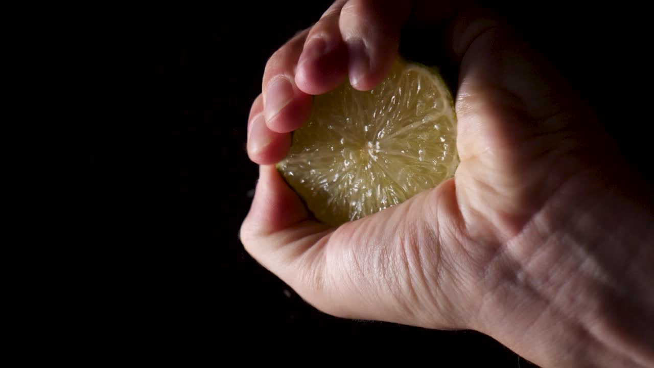 Male hand Squeeze Lime, Lemon Juice dropping on transparent surface